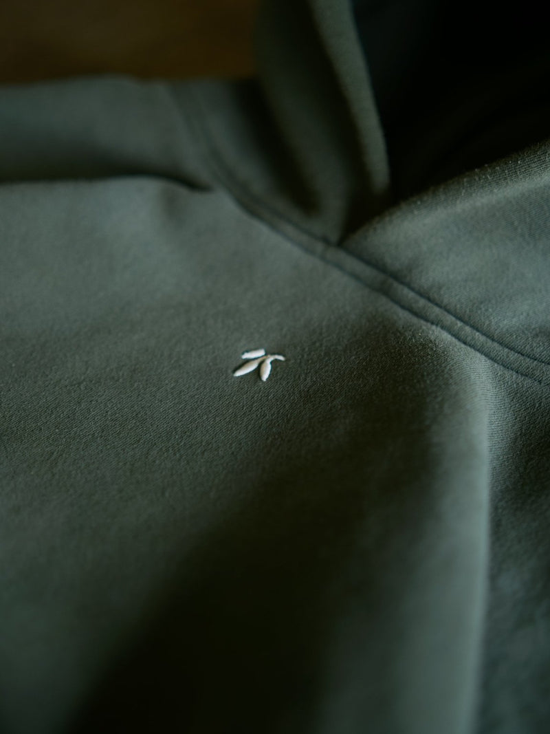 Goji Longevity forest green hoodie — close-up embroidery and fabric detail